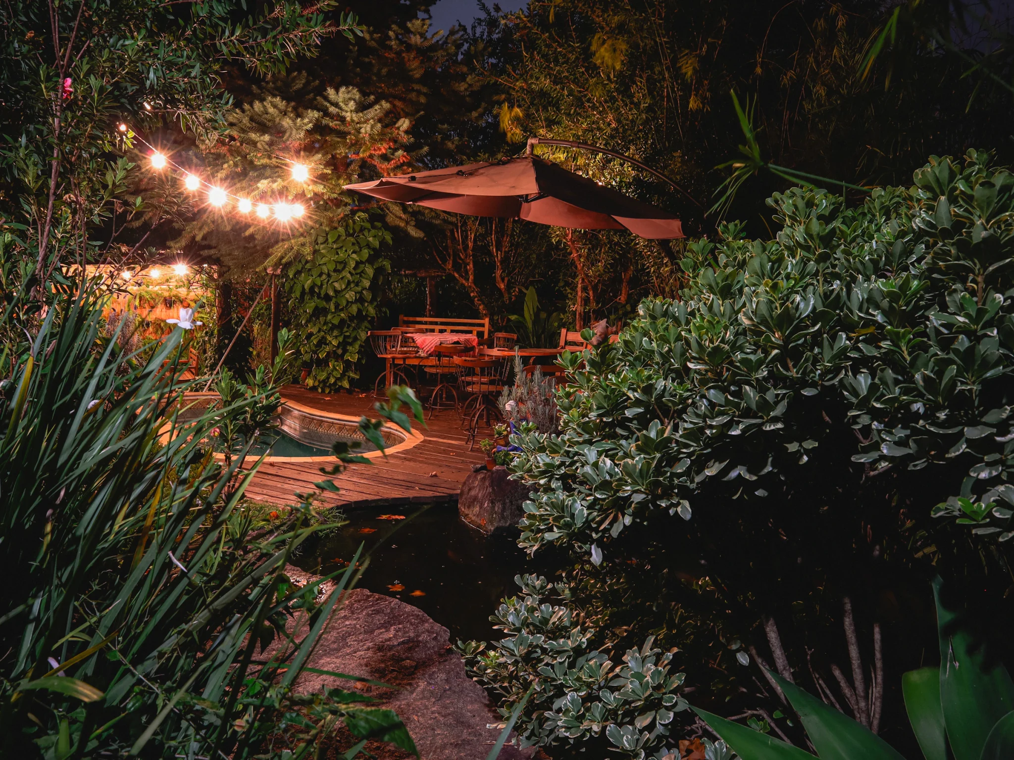 Backyard patio, garden and pool illuminated in the evening