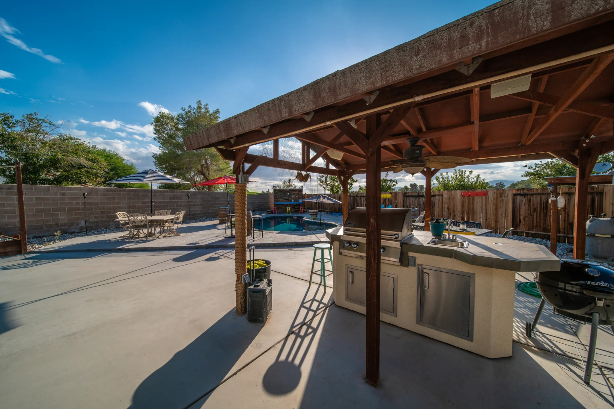 Covered patio with a grill station and dining table beside the house