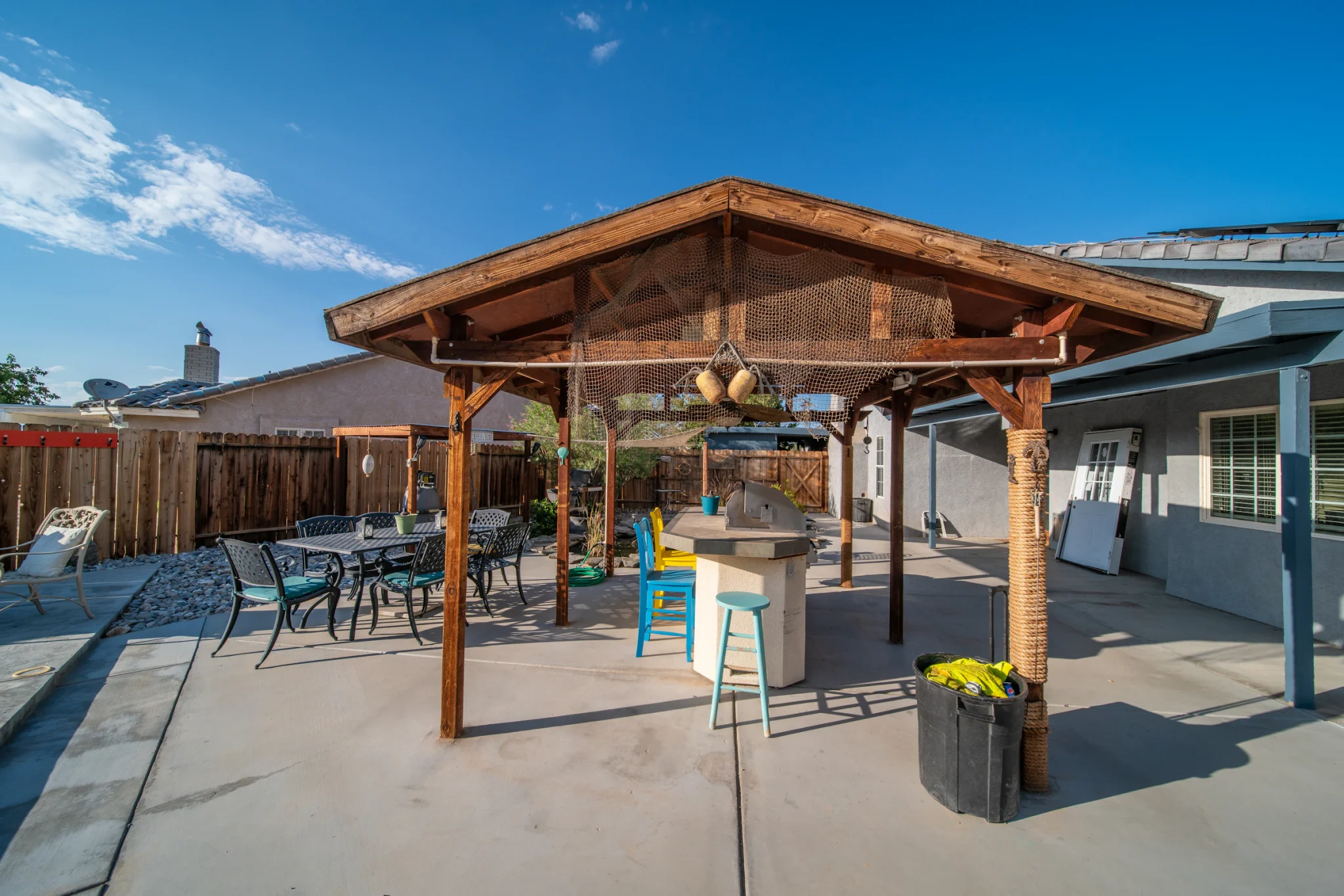 Covered backyard patio with an outdoor dining table under a modern shade structure