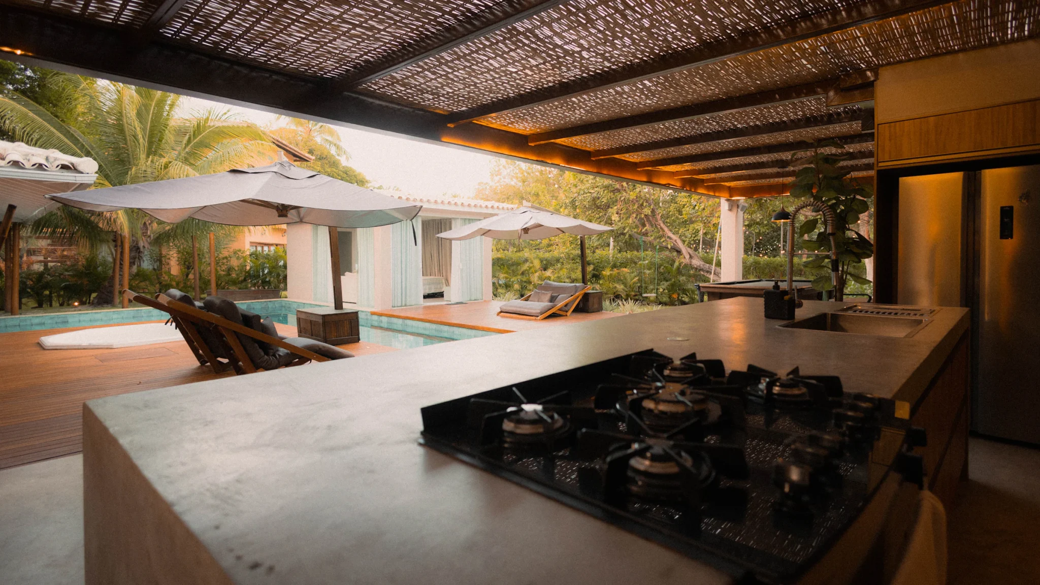 Modern outdoor kitchen with counters and seating next to a pool