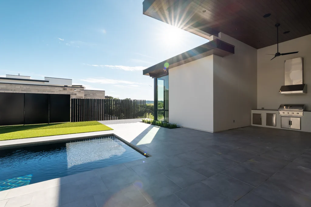 Outdoor kitchen and covered lounge area overlooking a swimming pool