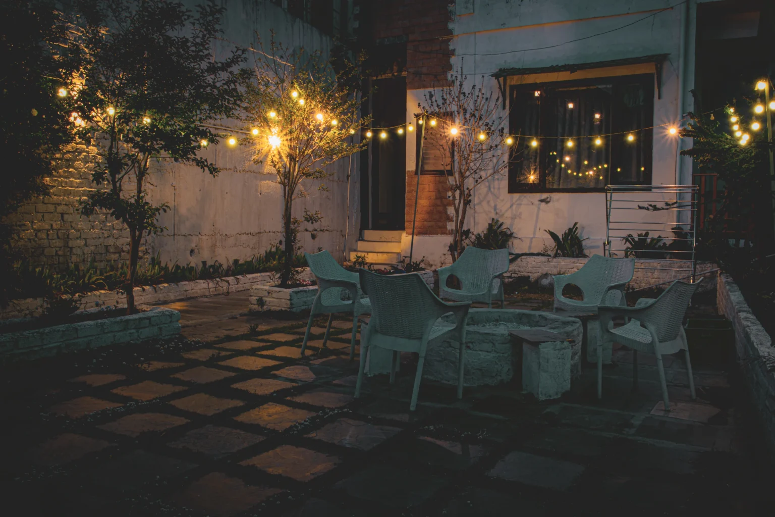 Patio table and chairs softly lit by outdoor lights at night